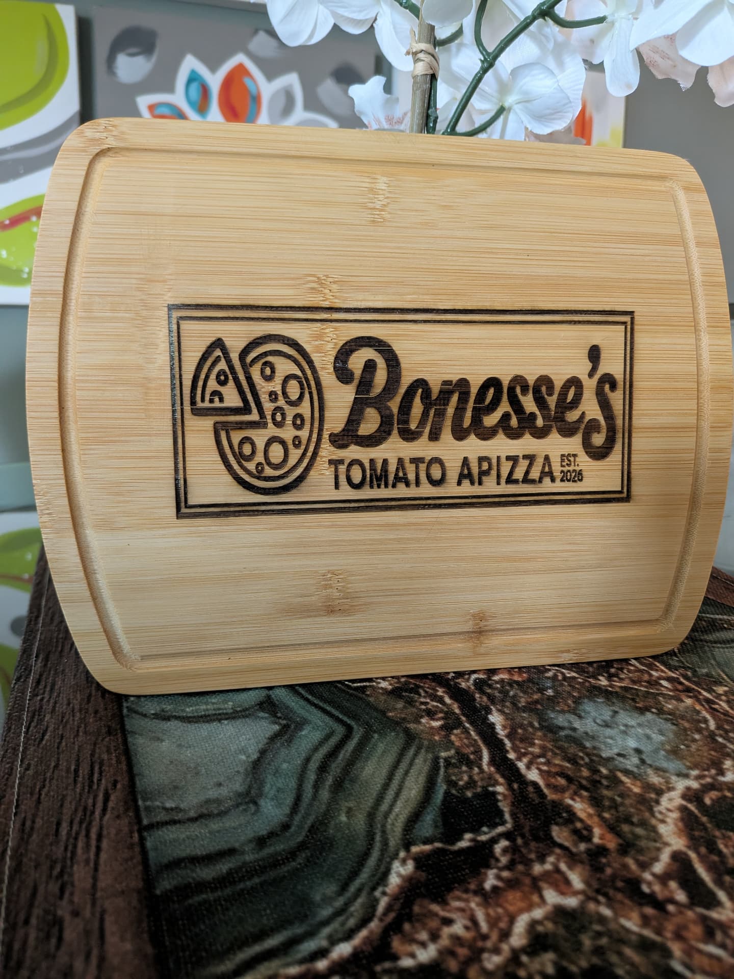 Engraved cutting board with a custom pizzeria logo reading Bonesse's Tomato Apizza, Est. 2026