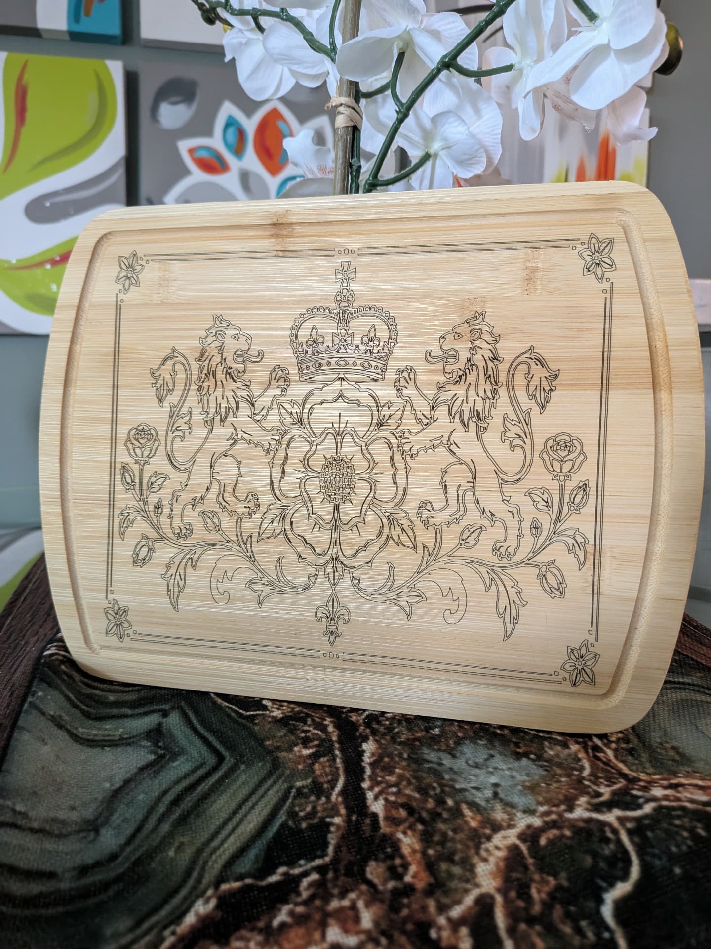 Engraved cutting board with a heraldic crest of two lions, a crown, and roses